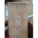 A Chinese pink wool rug with a floral pattern to the centre and the borders, 153cm x 92cm approx.
