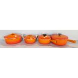 A collection of Le Creuset kitchen ware in burnt orange, including two casserole dishes and an