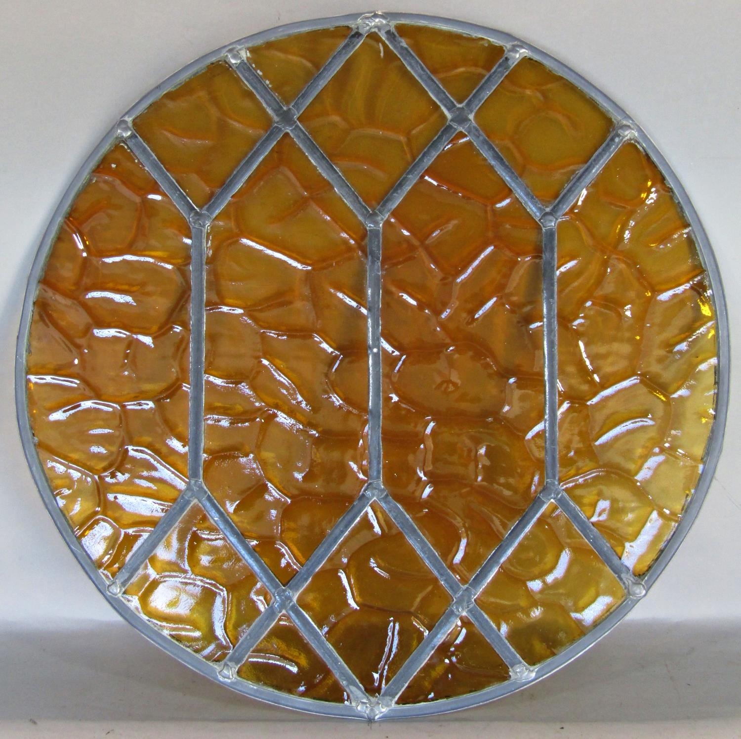 An art deco leaded light panel with amber coloured glass, 51cm diameter, with travel case