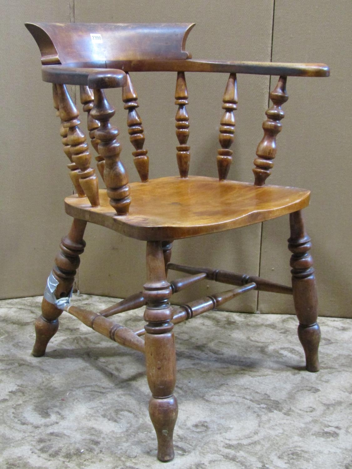 An antique Windsor smokers bow elbow chair in birch and stained beechwood raised on turned