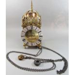 A traditional old English style lantern clock with brass case, silvered dial and timber wall bracket