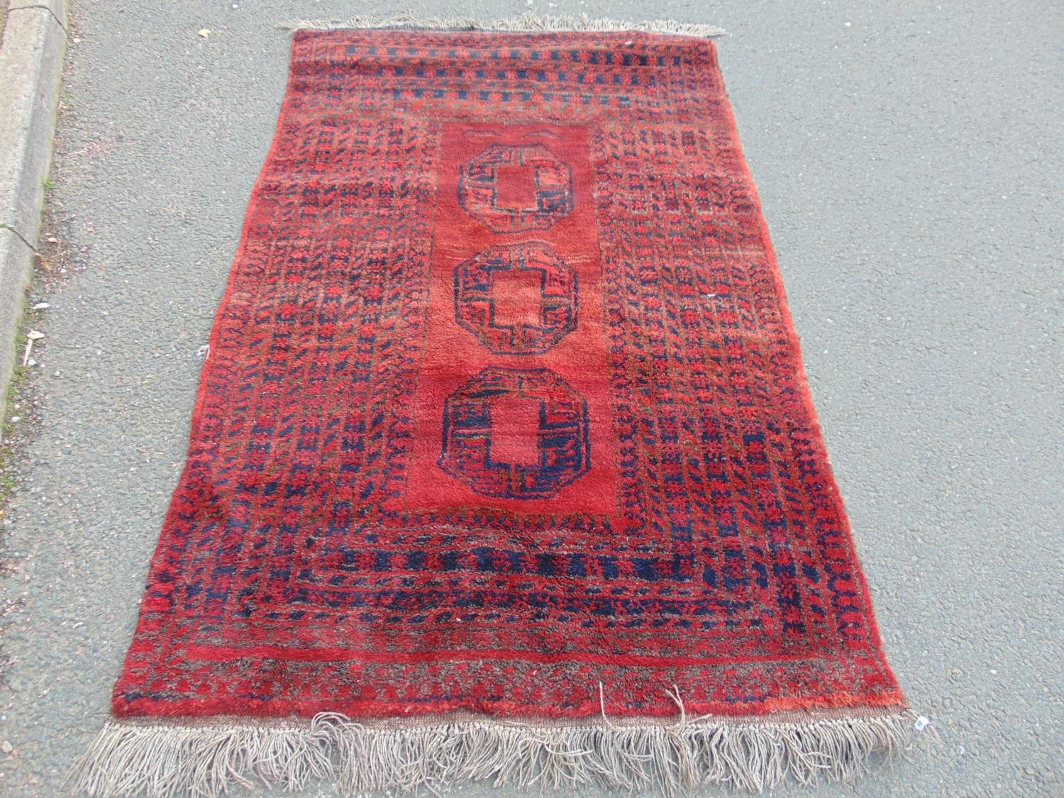 A Middle Eastern rug with a central panel of three guls and a radiating rectangular geometric