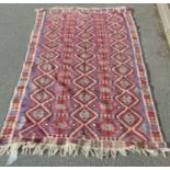 An old Middle Eastern kilim carpet with a bright overall geometric pattern, faded to the reverse,