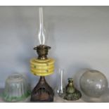 A Victorian oil lamp with mustard coloured font and cast iron base, together with further oil lamp