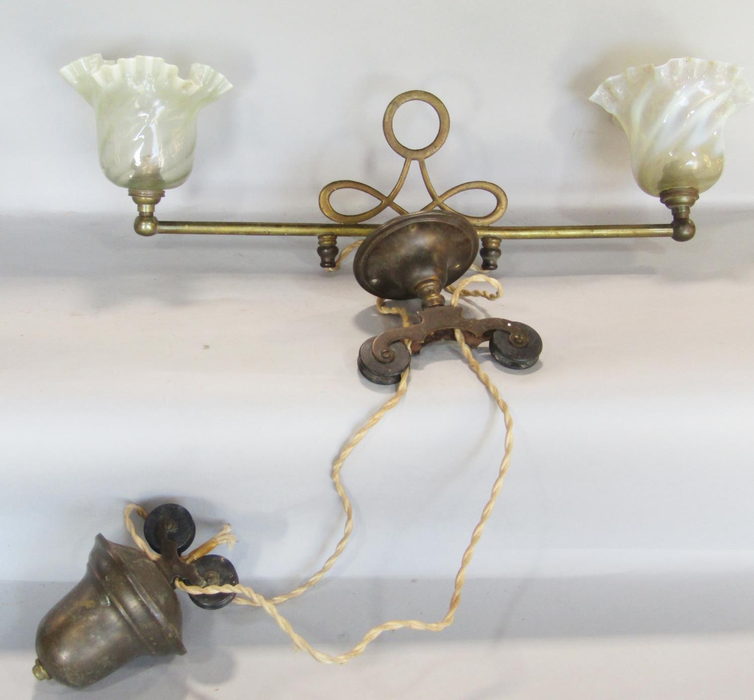 An Edwardian brass two branch rise and fall ceiling light with Vaseline glass shades, with wrythen