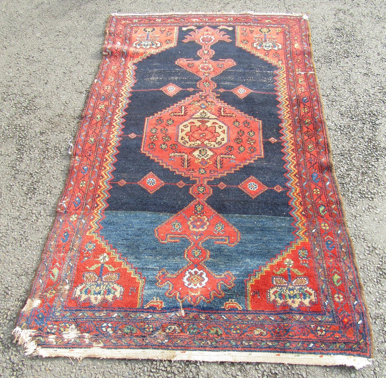 An old Kazak carpet with a central extended medallion and stylised flowers on a dark blue ground,
