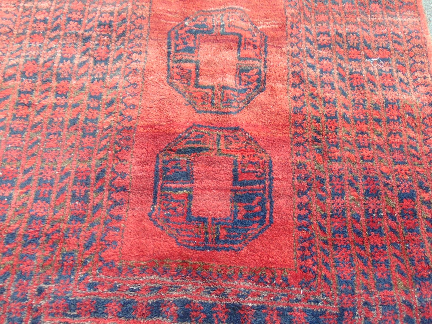 A Middle Eastern rug with a central panel of three guls and a radiating rectangular geometric - Image 2 of 3