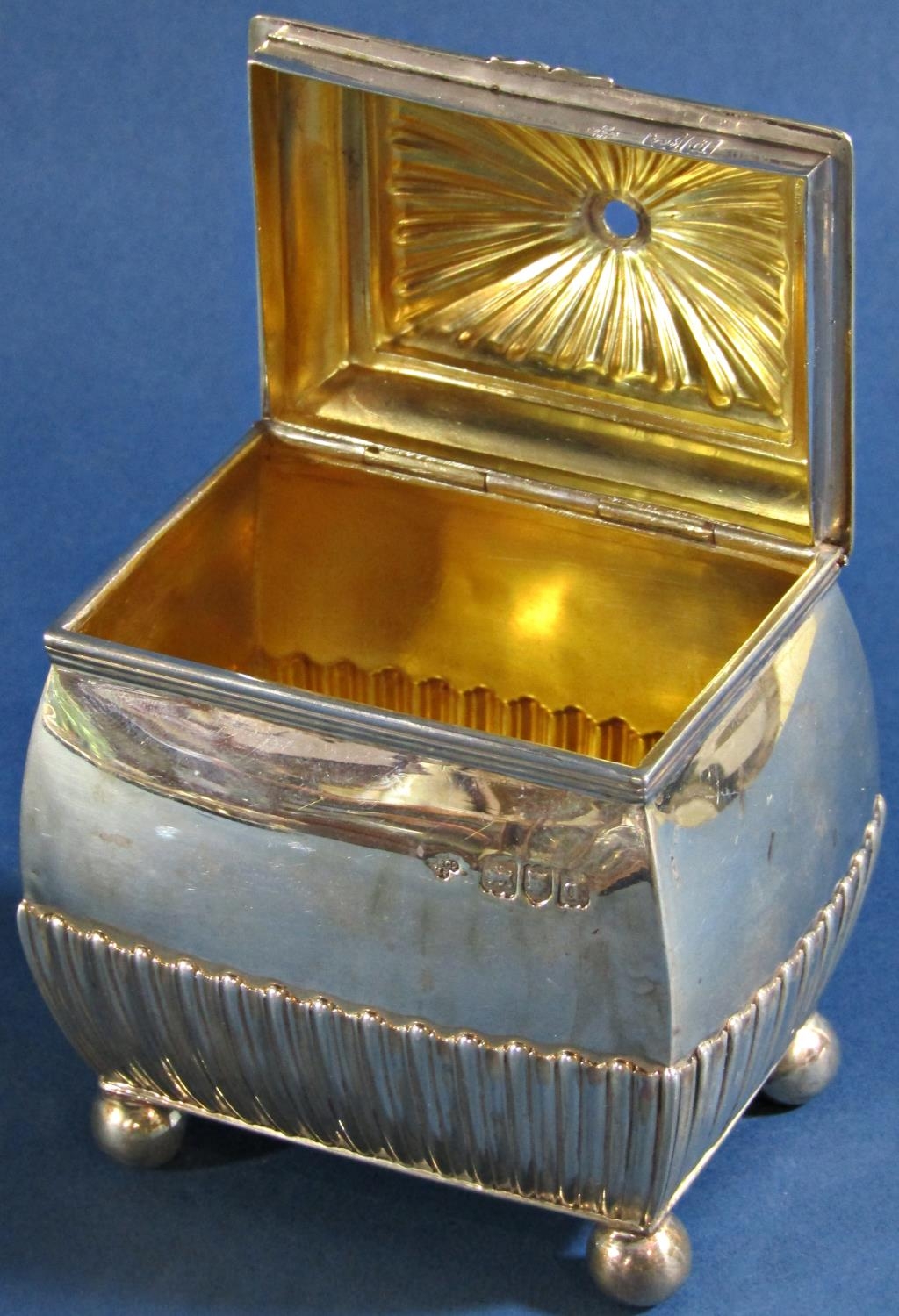 A silver sugar bowl with a hinged lid (lacks finial) half gadrooned sides, raised on ball