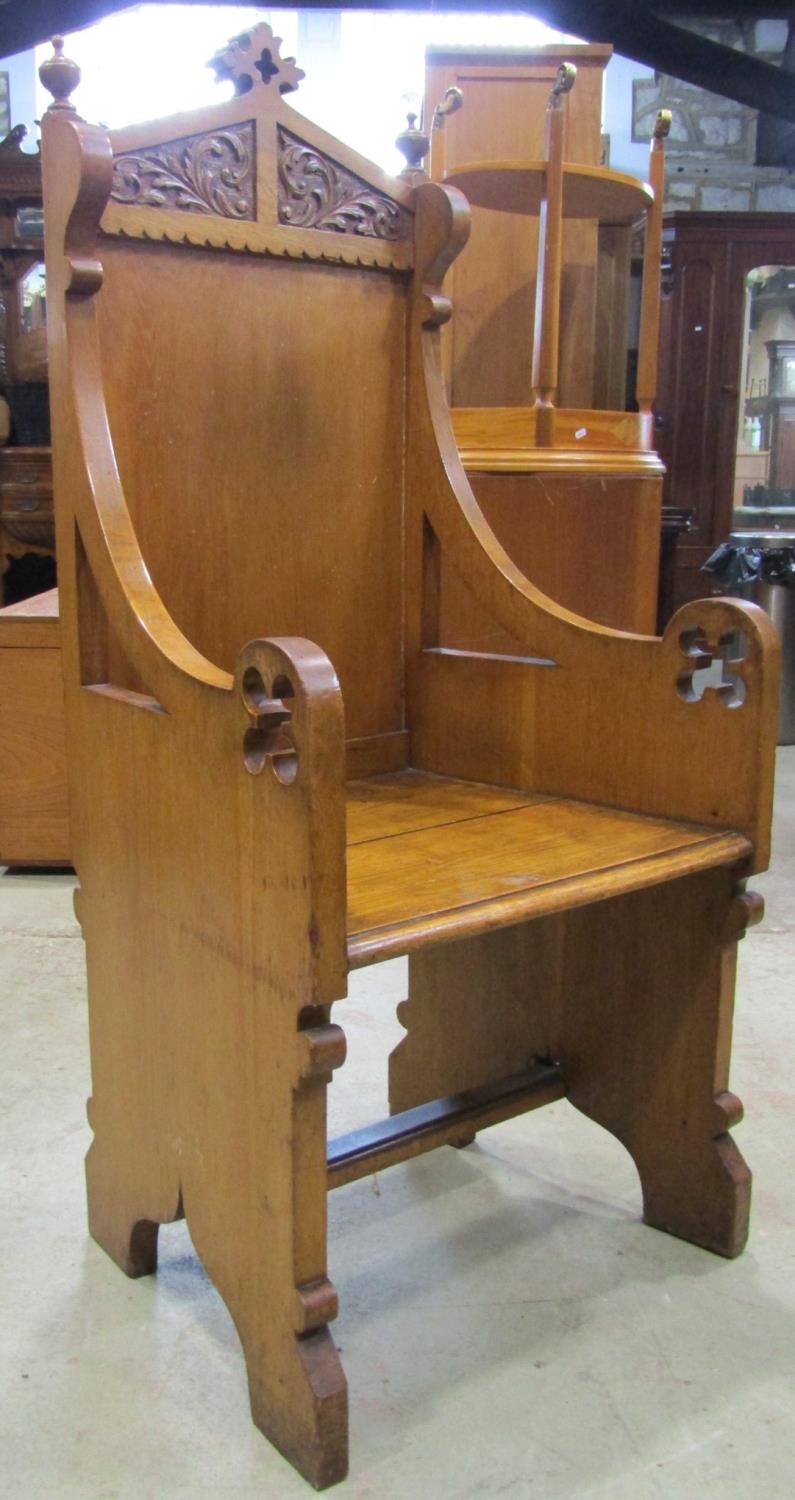 A Victorian gothic oak throne/church chair with shaped and moulded outline, downswept arms and