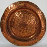 An early 20th century hand beaten copper salver, 42cm diameter approx