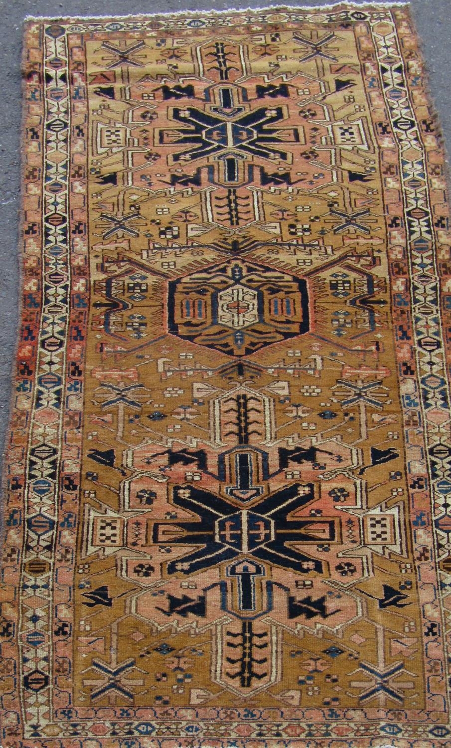 A North West Persian Heriz Runner with a central row of geometric symbols on a pale brown ground,