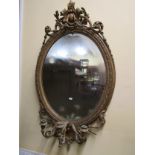 A 19th century girondelle ,the oval gilt gesso frame with scrolling and trailing foliate detail (