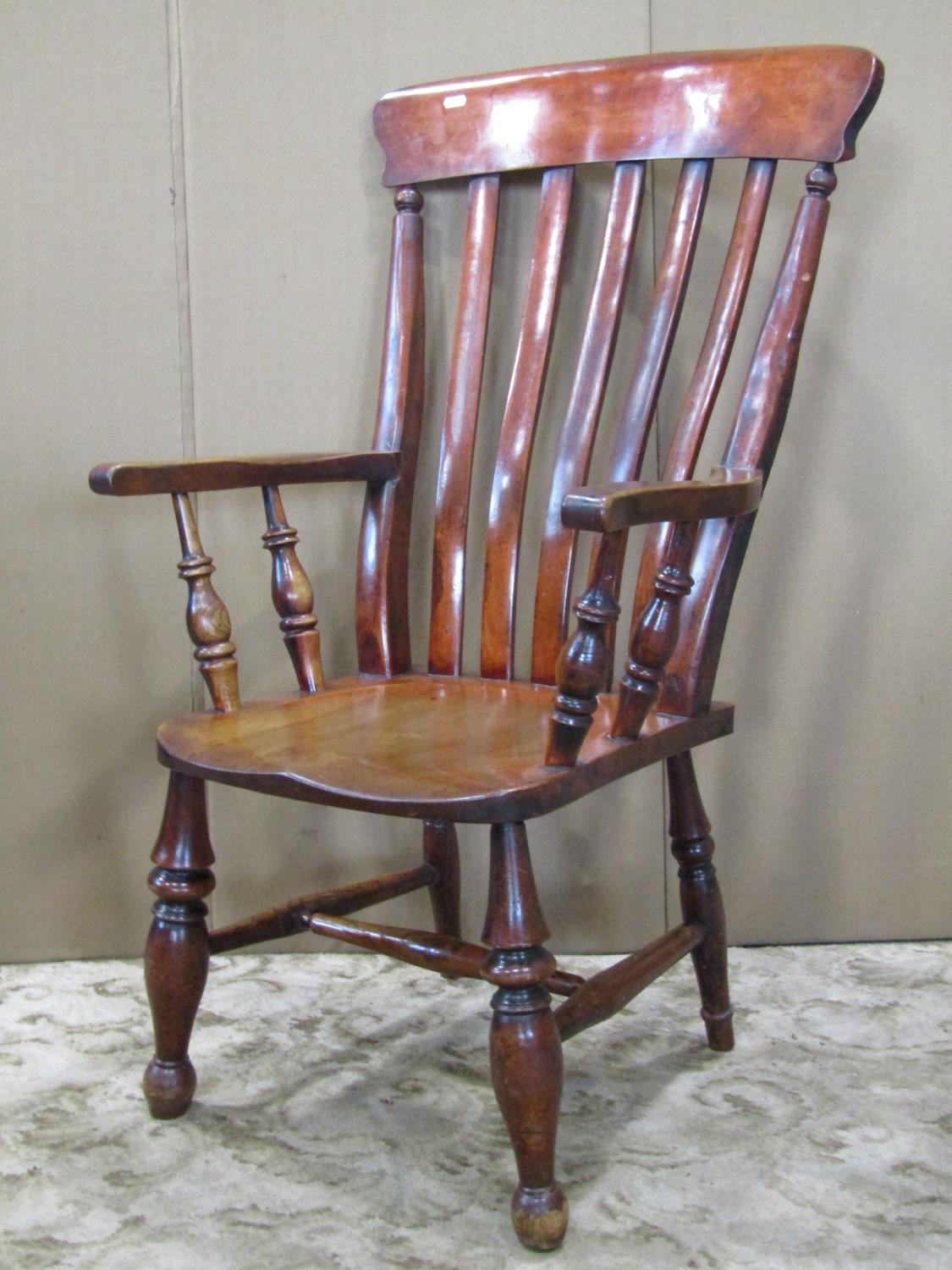 A Windsor stained lathe back armchair with saddle shaped seat raised on turned supports and