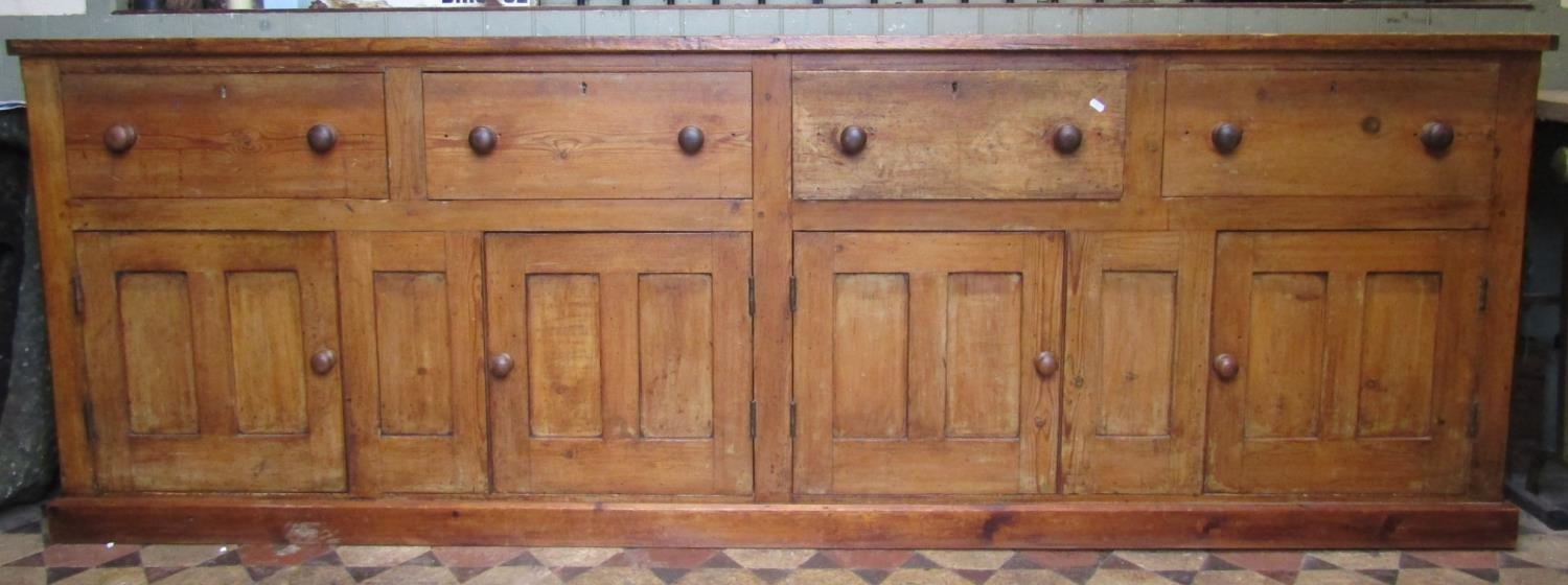 A large pine farmhouse kitchen dresser base partially enclosed by four twin rectangular panelled