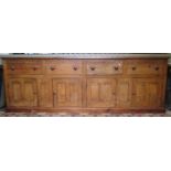 A large pine farmhouse kitchen dresser base partially enclosed by four twin rectangular panelled