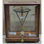A good quality lacquered brass laboratory scale housed within a glazed mahogany case, scale
