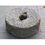 A weathered granite mill stone 42 cm diameter x 15 cm thick