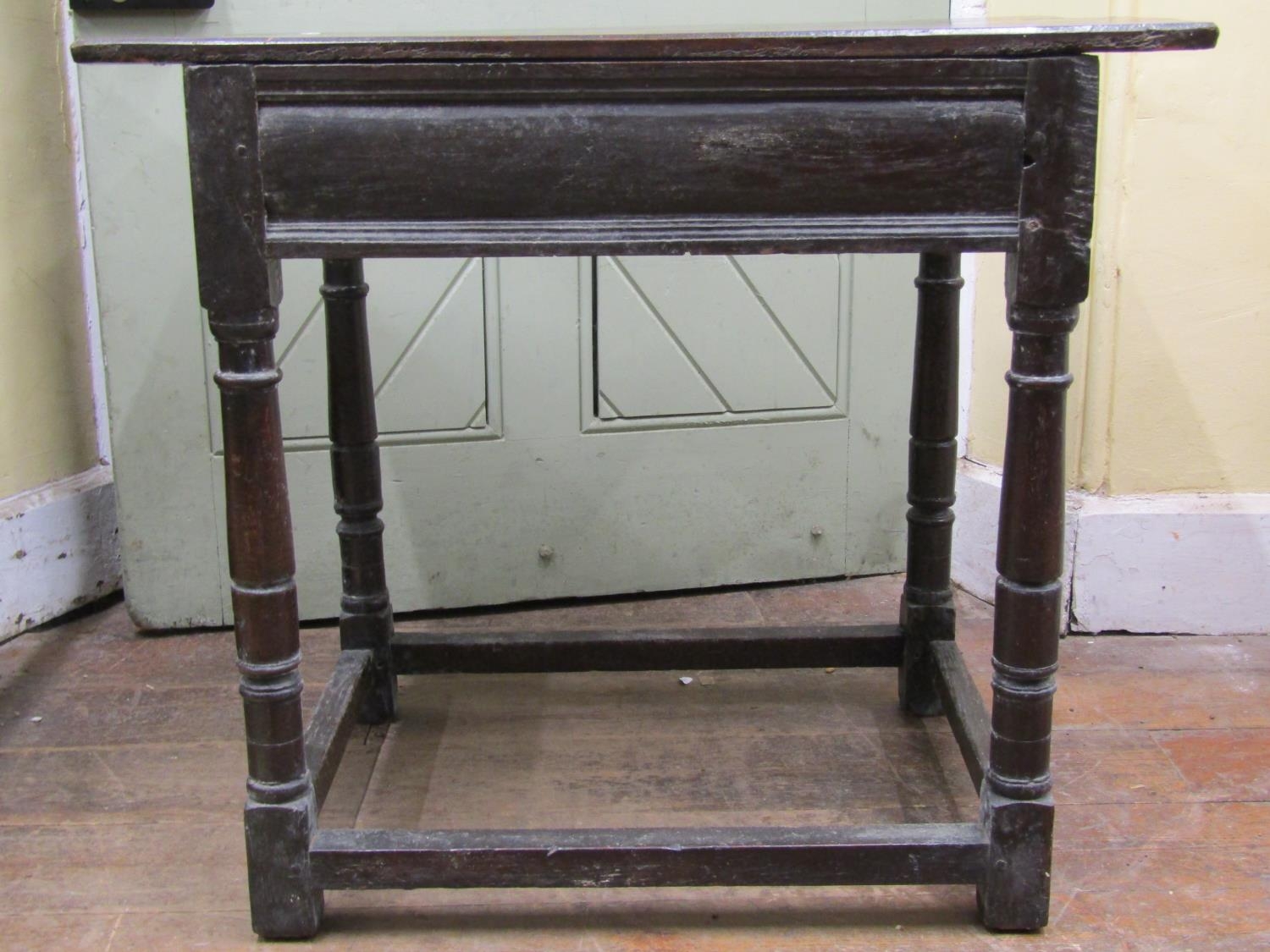 An 18th century oak side table the plank top raised on four turned supports and enclosing a frieze - Image 3 of 3