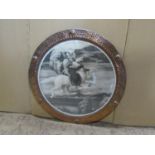 An Arts & Crafts style circular planished frame enclosing a sepia black and white print, 59 cm