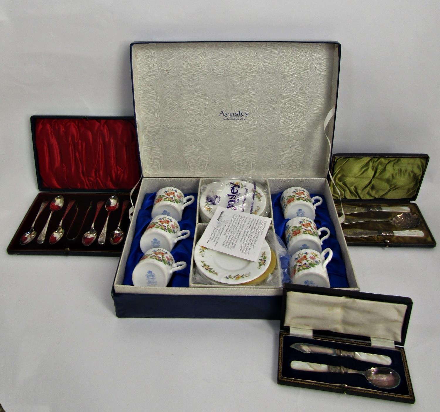 A silver plated filigree cake stand with handle, a square Art Deco teapot, four cased sets of silver