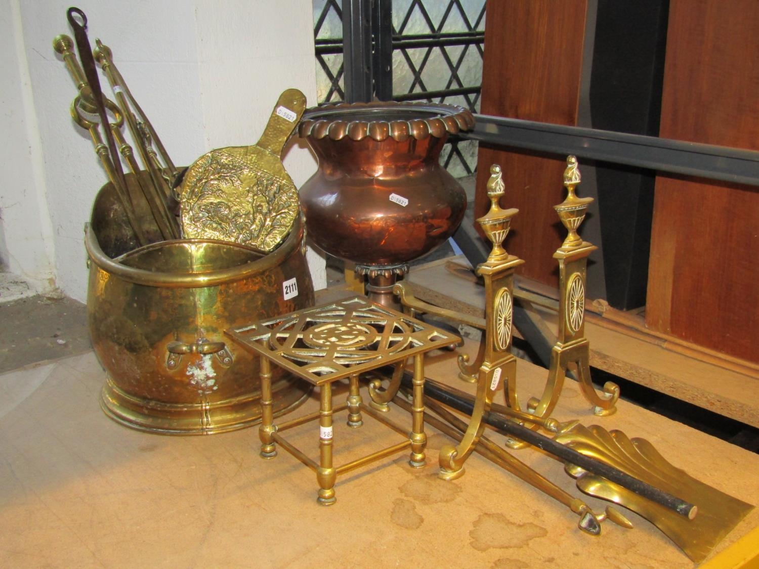 A brass helmet shaped coal scuttle, pair of brass Adams style fire dogs, sundry fire irons, trivet