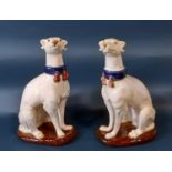 A pair of continental glazed figures of seated hounds wearing tasselled collars, 36cm high