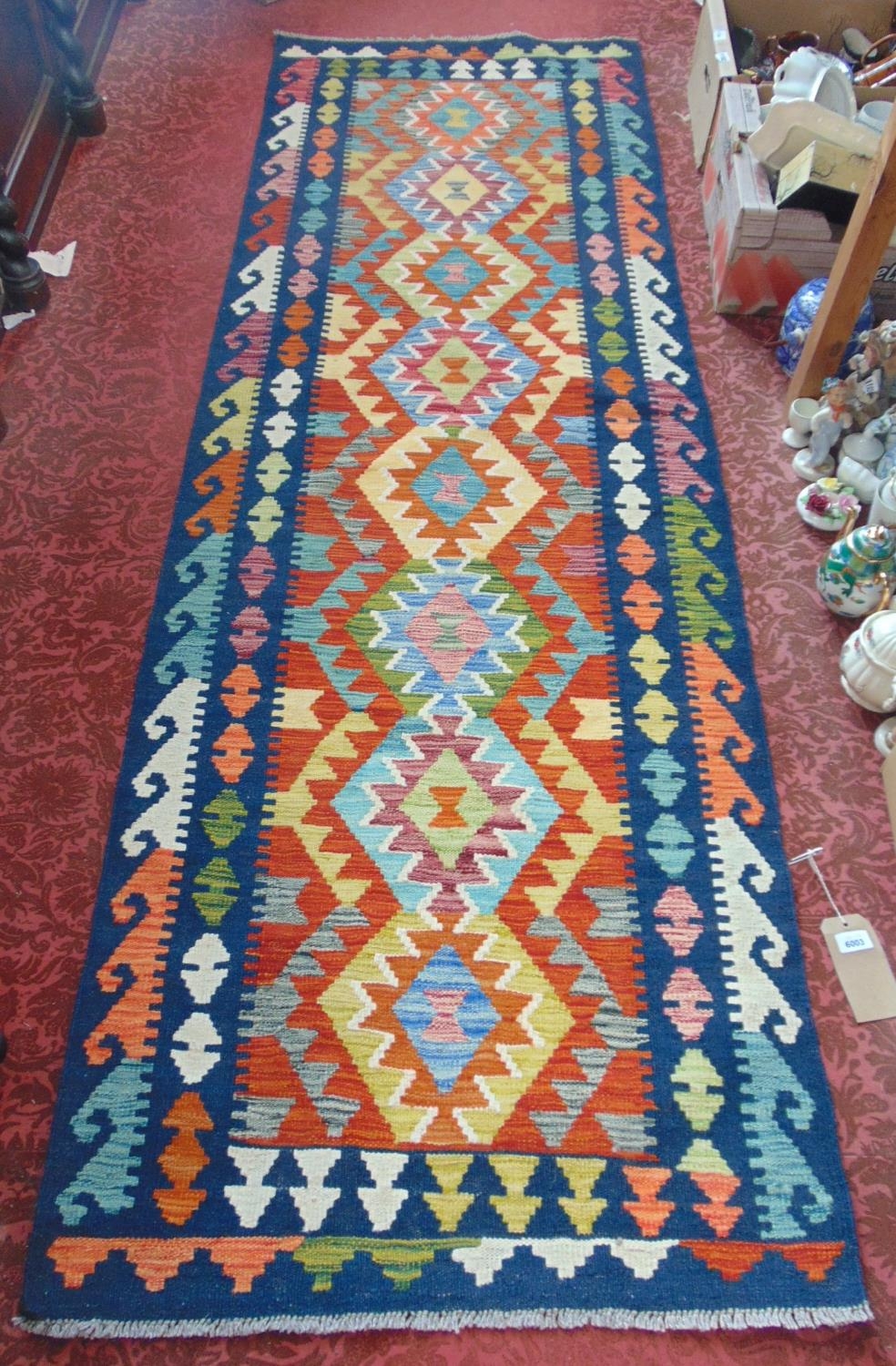 A Chobi Kilim runner with a central panel of multi coloured diamonds on a dark blue ground, 250cm