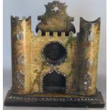 A Victorian papier mache watch holder in the form of a castle entrance with mother of pearl inlay