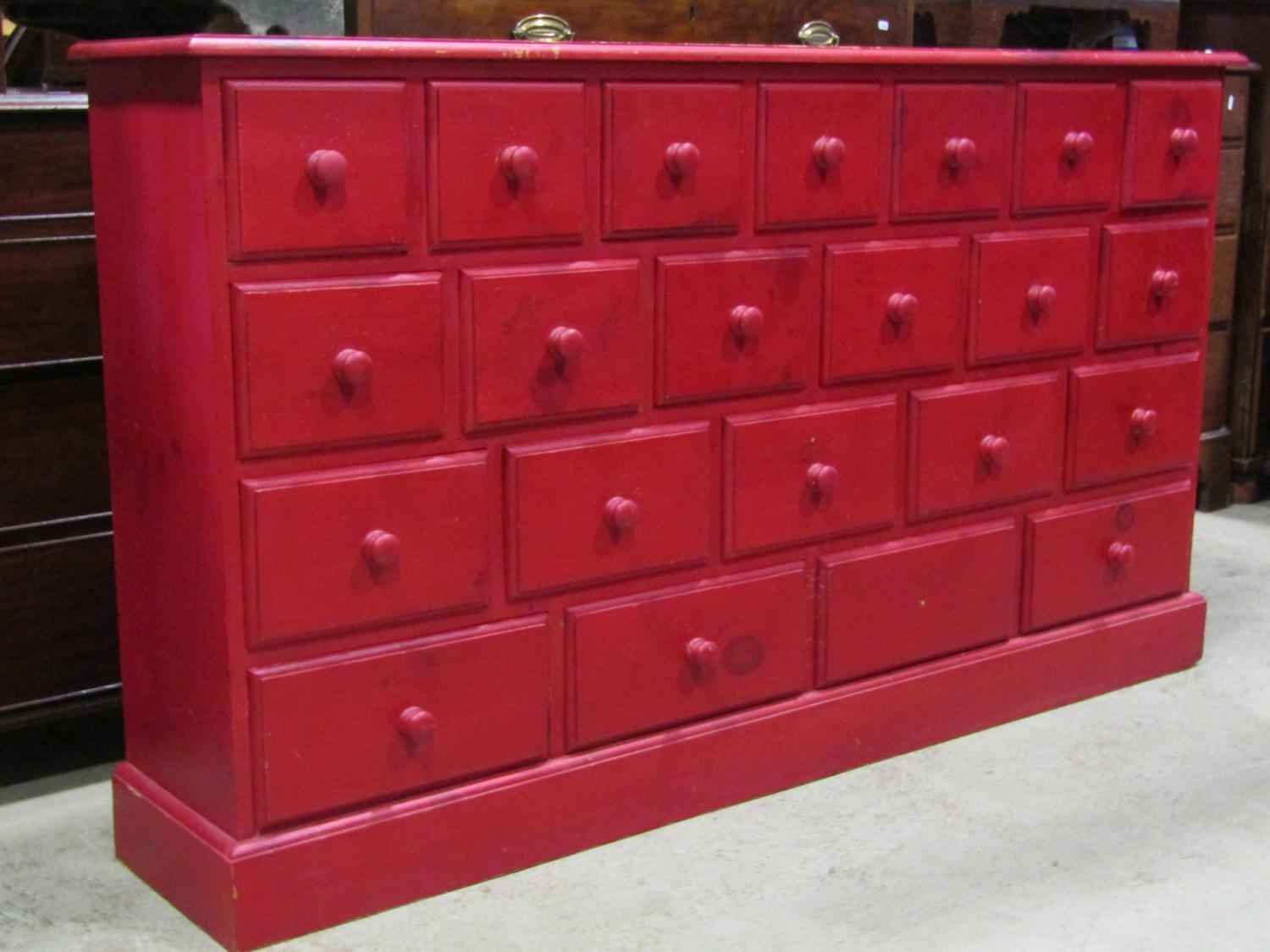 A narrow floorstanding dresser fitted with an arrangement of 22 drawers with stained finish raised