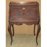 An Edwardian mahogany writing bureau with shaped and moulded outline, patent fall flap with