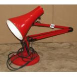 An anglepoise 90 table lamp in red, raised on a domed disk shaped base,