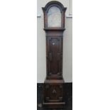 An Edwardian oak grandmother clock with arched brass dial and engraved detail, enclosing a three