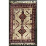 A Baluchi carpet with an interlocking central lozenge in the hues of purple, red and green on a