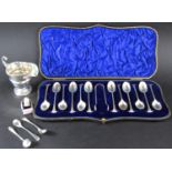 A cased set of twelve teaspoons and a sugar tong, silver cream jug, three mustard spoons, a thimble,