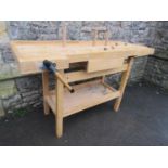 A freestanding work bench in beech with two vices and incorporating a central frieze drawer,
