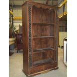 An Indian hardwood freestanding bookcase with decorative metal grill borders and frieze drawer,