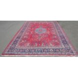 A large Kashan style carpet with a central floral medallion surrounded by stylised flowers on a