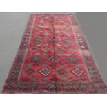 A Bokhara style carpet with an all over geometric hexagonal pattern on a red ground, 290cm x 152cm