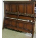 A 1920s oak bedstead in the old English style with panelled head and footboards with foliate and