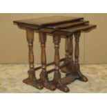 A nest of three good quality Old English style graduated occasional tables raised on turned supports