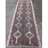 A middle eastern design runner with two runs of interlocking medallions on a dark brown ground.