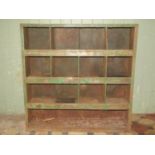A vintage industrial segmented open shelving unit with remains of original green painted finish,