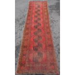 A faded and worn old Turkoman runner with a row of ten central elephant foot guls on an orange