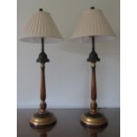 A pair of good quality table lamps, the polished timber highlighted with gilded sections set with