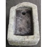 A weathered thick walled rectangular natural stone trough with single D end 57 cm long x 38 cm