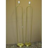 A pair of contemporary brushed brass effect standard lamps with elongated tubular loop stems set