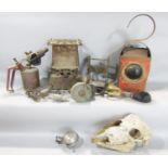 A miscellaneous collection of items including a sheep's skull, a rusty red roadside lantern, a rusty