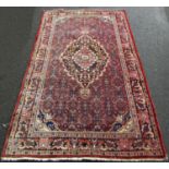 An old slightly worn Hamadan carpet with a floral medallion on a field of stylised flowers. 220cm