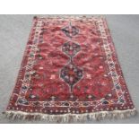 A Middle Eastern carpet with triple linked lozenge on a red ground, 190cm x 140cm approx.