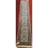 A narrow Middle Eastern runner with a repeating pattern in pale blues and brown, 330cm x 56cm